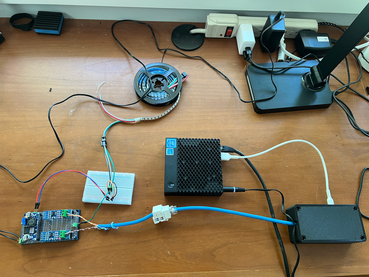 Project spread out on my desk, including a Dell Wyse 3040 thin client, the USB interface board in a 3d printed box, the RS485 receiver board hooked up to a spool of LEDs via a breadboard.