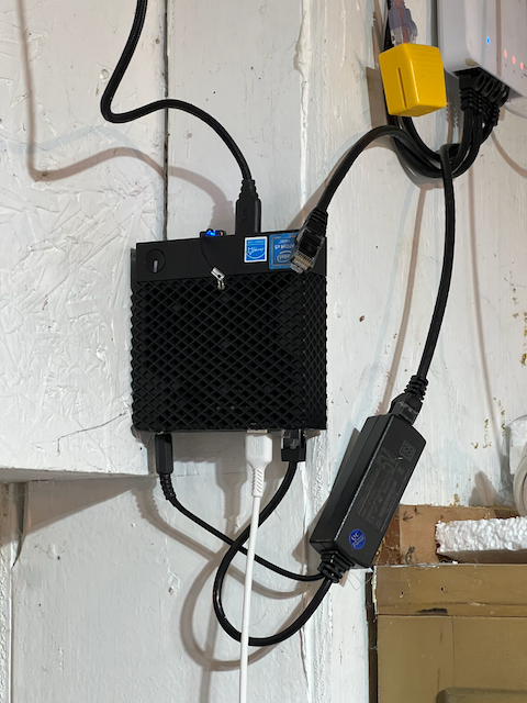 a Dell Wyse 3040 hanging on a wall with a PoE splitter hanging next to it